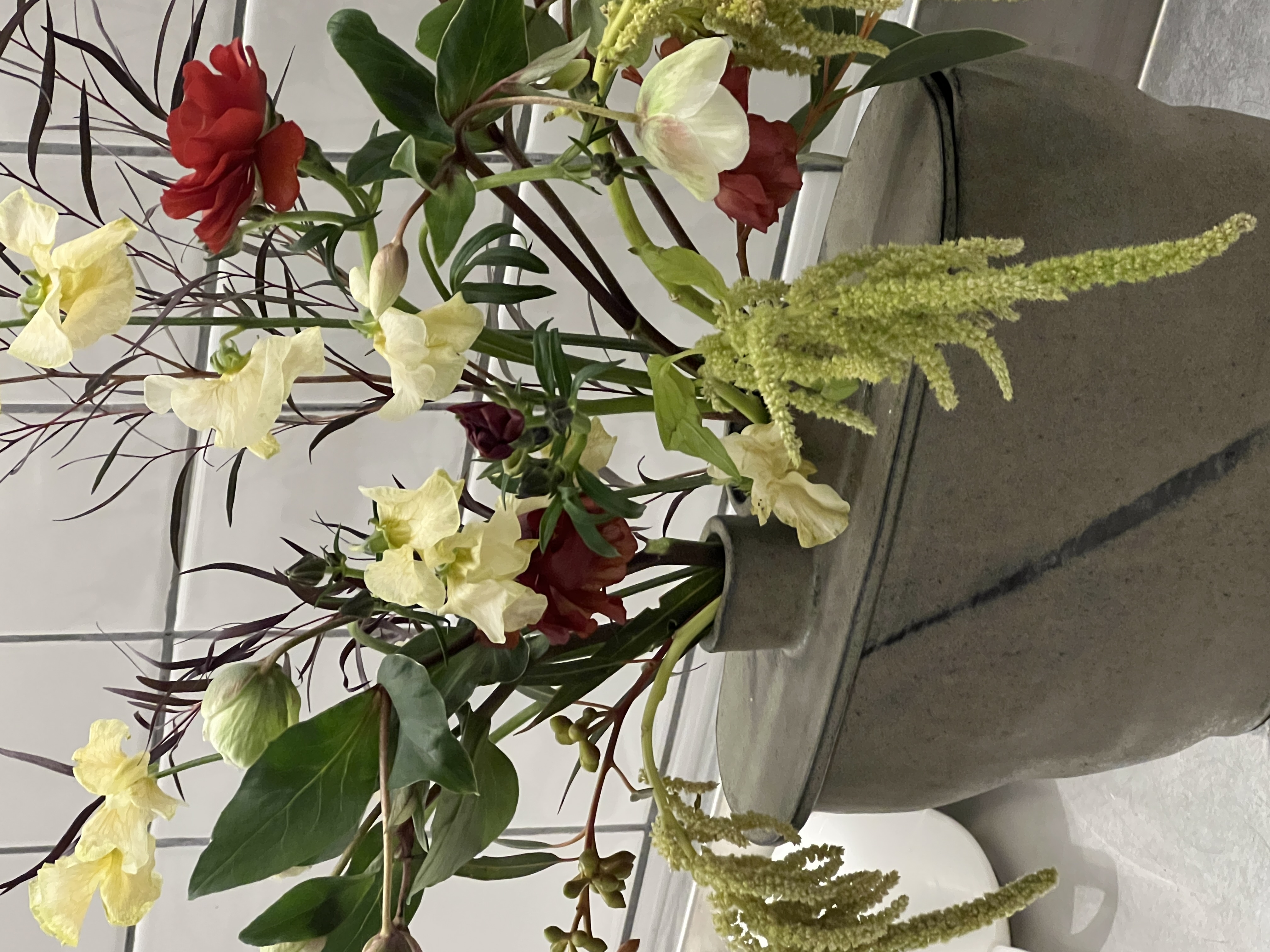An arrangement of flowers and greenery in a ceramic vessel.