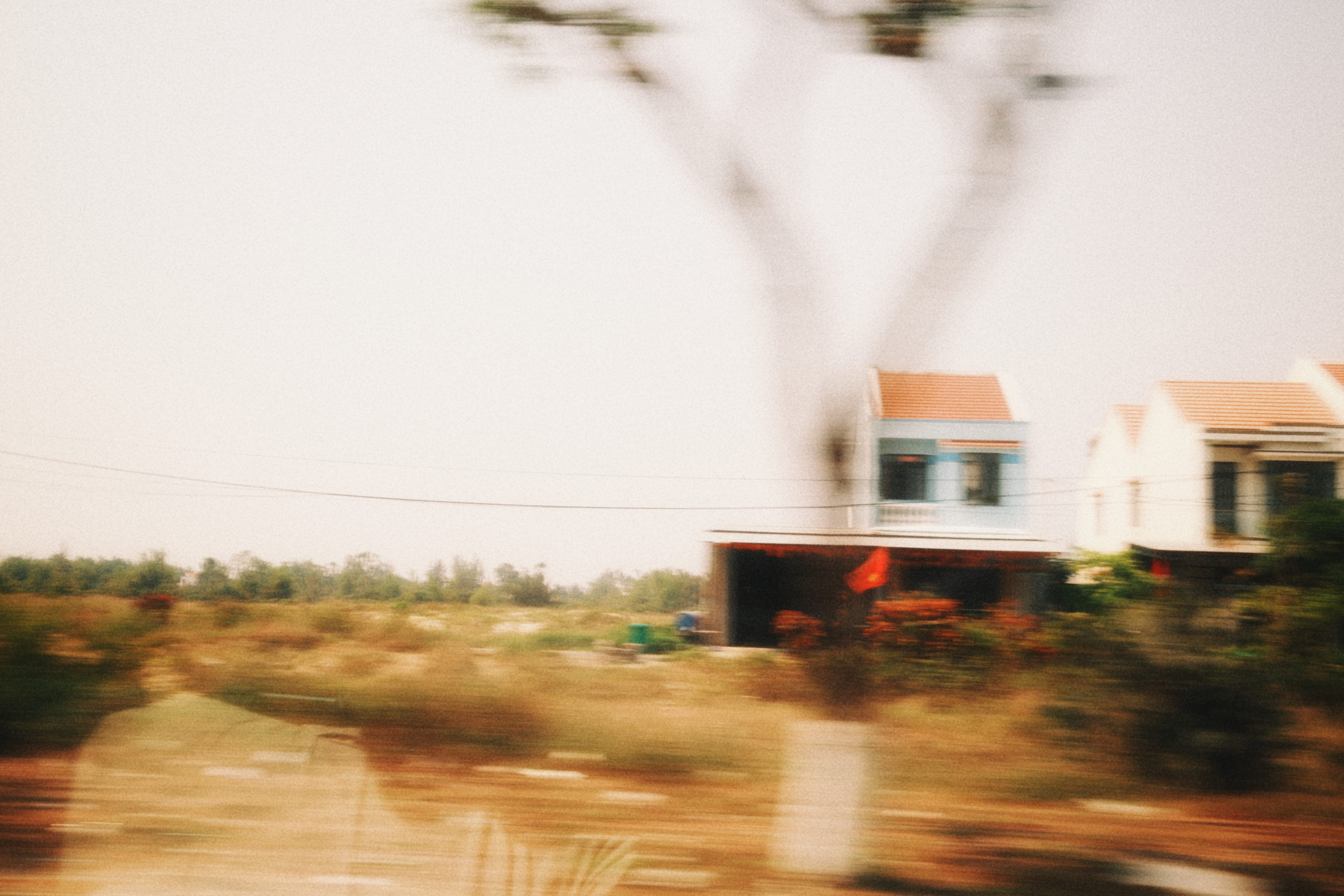 A passing landscape with houses and warm, blurred greenery.