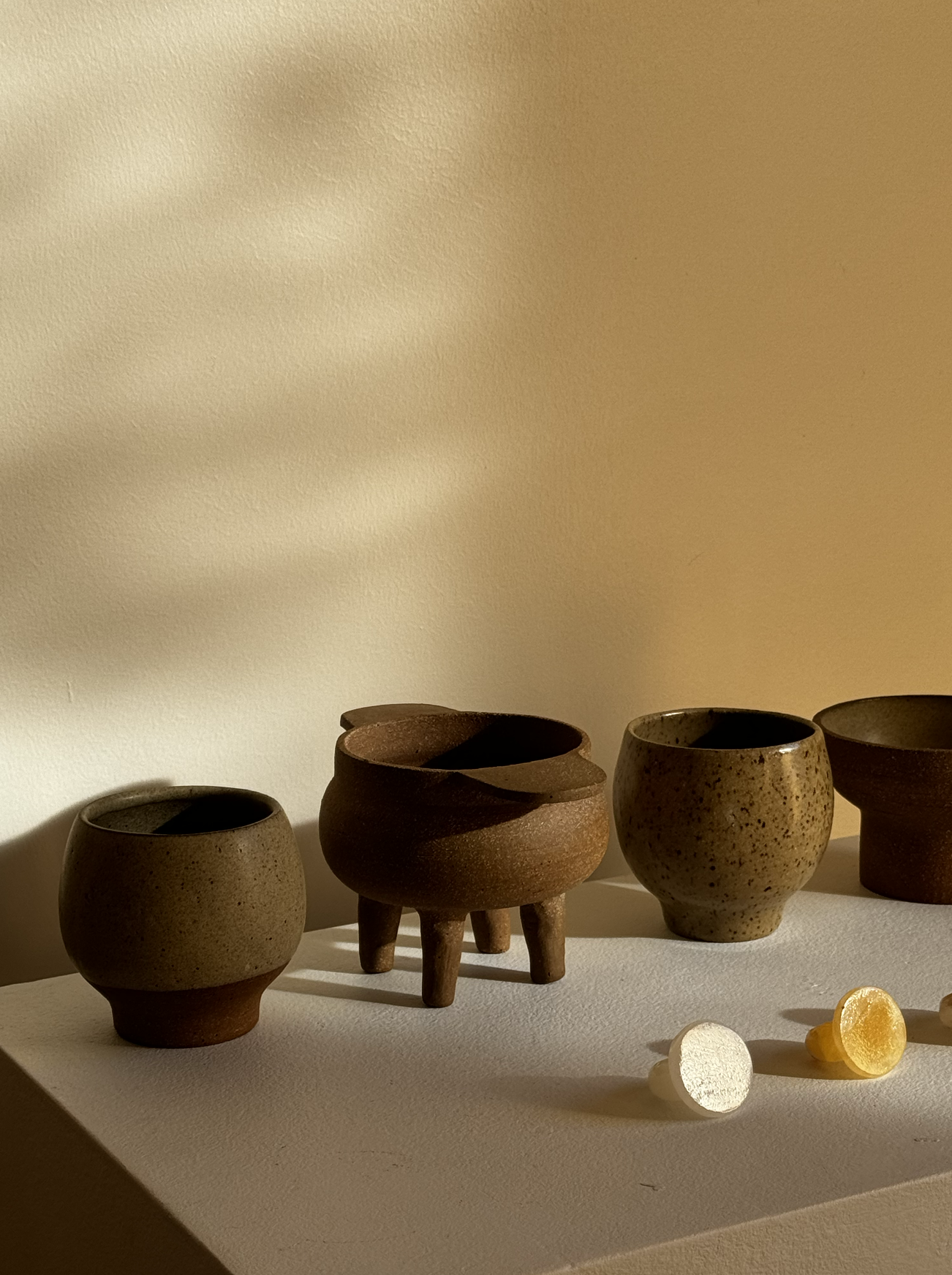 Handmade ceramic bowls in warm sunlight with small yellow fruit.